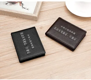 Detailed view of two genuine leather litchi grain driver's license covers on a wooden desk