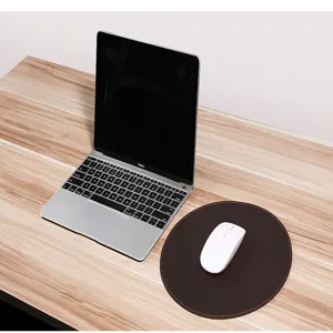 Vue détaillée du tapis de souris circulaire en cuir Crazy Horse marron foncé sur un bureau en bois