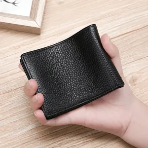 Black genuine leather driver's license holder with lychee pattern held in hand against wood background
