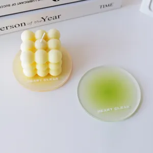 Frosted green and orange acrylic coasters with a cream bubble candle on white desk