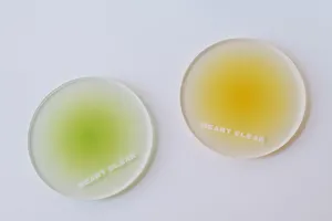 Detail view of two frosted acrylic coasters with green and yellow gradient centers.