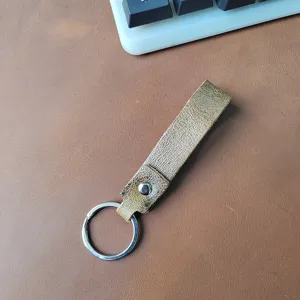 Primer plano de un llavero de cuero vintage sobre una superficie marrón texturizada