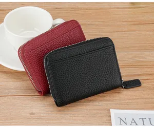 Close-up of leather accordion card holders in black and burgundy on a wooden table