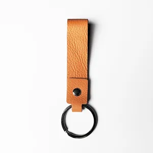 Llavero minimalista de cuero genuino marrón con anillo metálico sobre fondo blanco