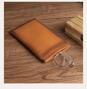 Close-up of tan leather squeeze-top pouch showing functionality with eyeglasses