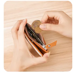 Detail showing a hand inserting coins into a brown leather RFID blocking coin purse