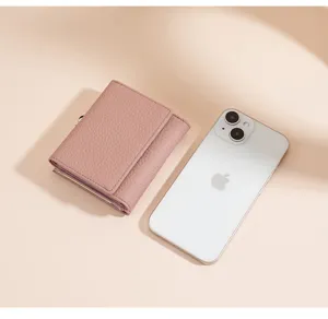 Kompakte rosa Ledergeldbörse für Damen neben einem Smartphone zum Größenvergleich