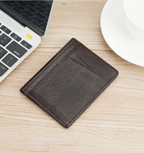 Close-up macro view of a dark brown pebble-grain leather card holder on a wooden desk