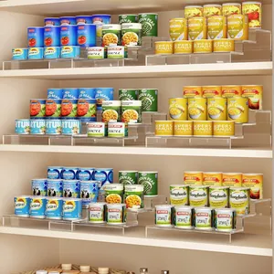 Macro view of tiered clear acrylic shelves organizing various food cans in a modern pantry.