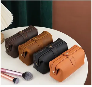 Four large leather makeup bags in varied colors displayed on a stylish vanity table