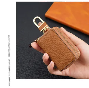 Detalle de una funda para llaves de coche en cuero granulado marrón sujeta a mano