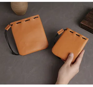 Handbediende weergave van twee retro oranje lederen trekkoordzakjes voor munten en sieraden
