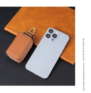 Detalle del estuche para llaves de coche en cuero marrón con doble cremallera y gancho
