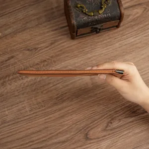 Ultra-thin brown leather coin purse with spring clip closure showing a slim profile view