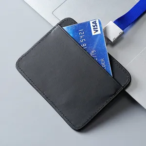 Minimalist genuine black leather ID badge holder with a blue lanyard on a laptop
