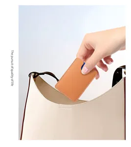 Orangefarbenes Leder-Kartenetui wird in eine elegante beige Umhängetasche gesteckt.