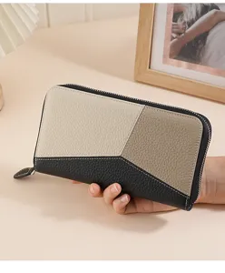 Leder-Geldbörse in Creme und Schwarz mit eleganter Kieselmaserung, in der Hand gehalten