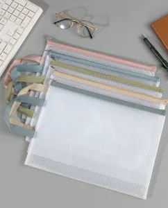 Stapel A4 Morandi mesh documententassen met ritsen en handvaten op een grijs bureau.