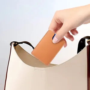 Schlanker Mini-Kartenhalter aus echtem Leder in Orange, der in eine weiße Tasche gesteckt wird