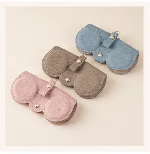 Three portable pebbled leather sunglass cases in pink, brown, and blue colors.