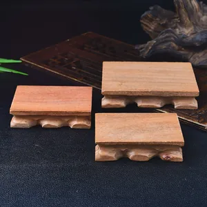 Dettaglio ravvicinato di tre basi in legno massiccio per esposizione con piedini intagliati.