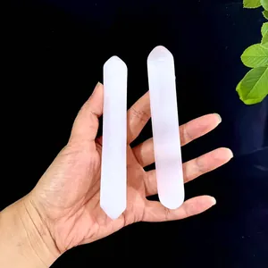 Hand holding two types of natural white selenite crystals with translucent texture