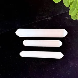 Detail view of three natural white selenite wands on a black textured background.