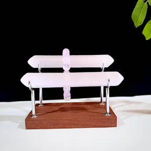 Close-up of natural pink selenite rods on a wooden jewelry display stand