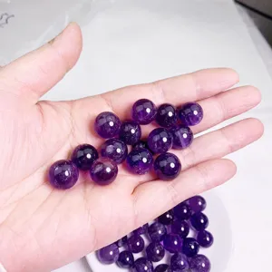 Close-up of high quality natural purple amethyst beads held in hand for scale demonstration