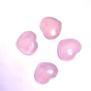 Gros plan de quatre pierres de quartz rose naturel polies en forme de cœur sur fond blanc