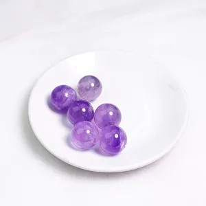 Set di sei sfere di cristallo di ametista viola naturale su un piccolo piatto bianco