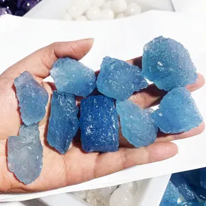 Detailed close-up of natural raw blue aquamarine stones held in hand, perfect for jewelry making.