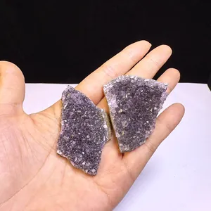 Dettaglio ravvicinato di due grappoli di ametista naturale dell'Uruguay tenuti in una mano