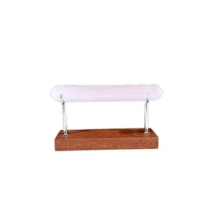 Natural Moroccan selenite wand presented on a minimalist wooden bracelet display stand
