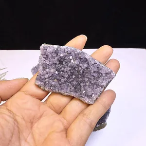 Dettaglio di una fetta di grappolo di ametista naturale dell'Uruguay tenuta in mano