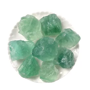 Piedras de cristal en bruto de fluorita verde natural para aromaterapia en plato blanco.