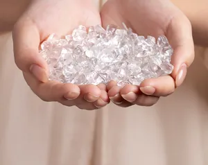 Close-up view of hands holding natural clear quartz crystal chips for purification