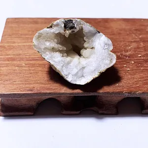 Detaillierte Ansicht einer natürlichen hohlen weißen Achat-Geode auf einem Holzsockel