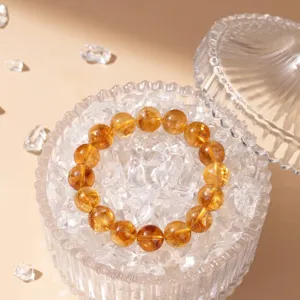 Natural citrine crystal bead bracelet displayed on clear quartz shards in a glass bowl