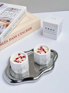 Close-up of handmade soy wax candles with red petals in marbled plaster cups