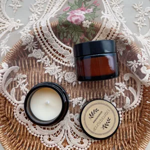 Close-up view of 35g soy wax scented candles in amber glass jars on decorative lace