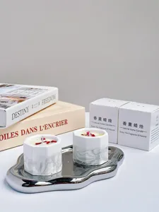 Detail of handmade soy wax candles in marble-patterned gypsum cups on a silver tray