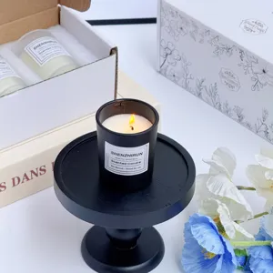 Gros plan d'une bougie parfumée noire à la cire de soja allumée sur un socle