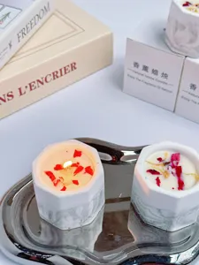 Close-up of handmade marble gypsum scented candle with dried flower petals and lit wick
