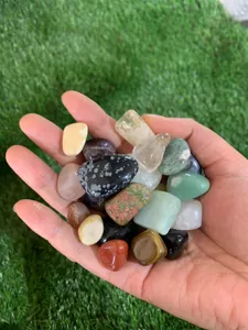 Gros plan de pierres de cristal naturelles colorées tenues à la main sur de l'herbe verte