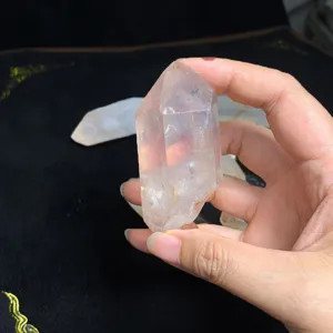 Pointe de cristal de quartz clair naturel tenue à la main pour décor et méditation.