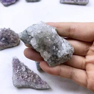 Nahaufnahme einer Hand, die eine natürliche Bergkristall-Stufe als Mineralienprobe hält