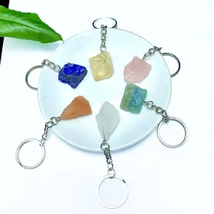 Various natural raw crystal stone keychains including rose quartz and lapis on white background