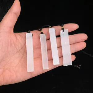 Natural white selenite bar pendant necklaces displayed on hand against black background