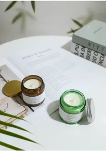 Close-up view of soy wax scented candles in amber and green glass jars with metallic lids